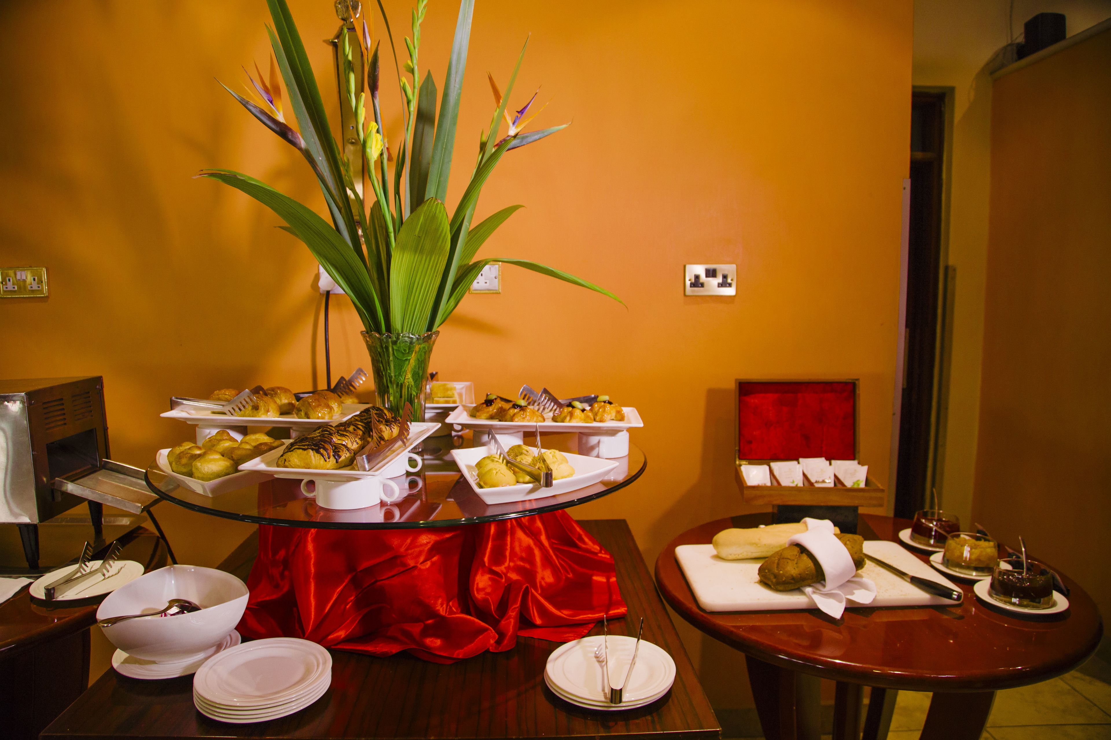A buffet table with various dishes, a red cloth, and a potted plant.