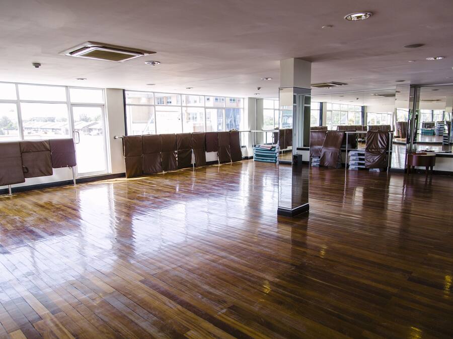 Um quarto amplo com piso de madeira, janelas grandes e parede espelhada.
