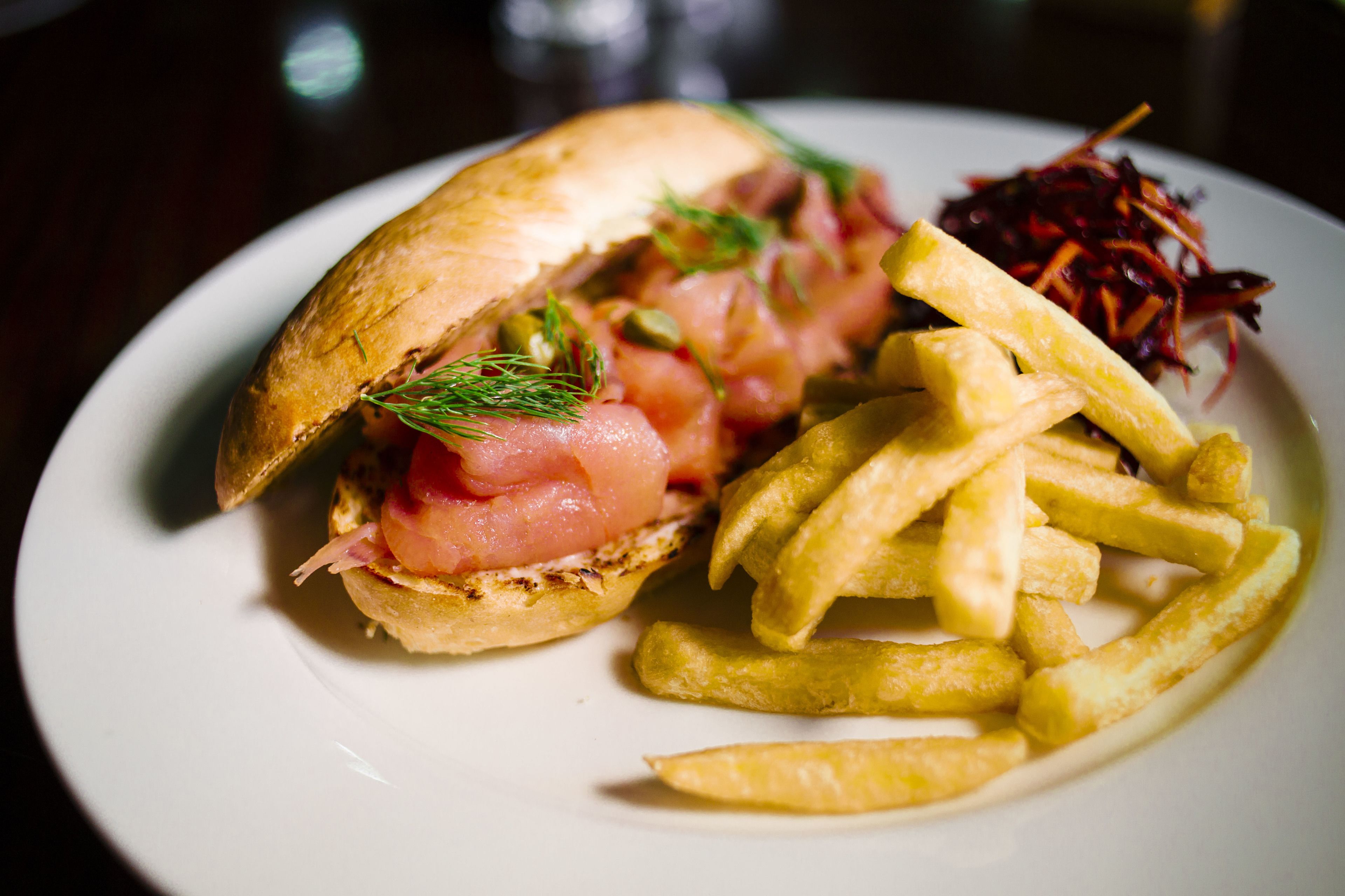 Un sándwich con pepinillos y una porción de papas fritas en un plato.