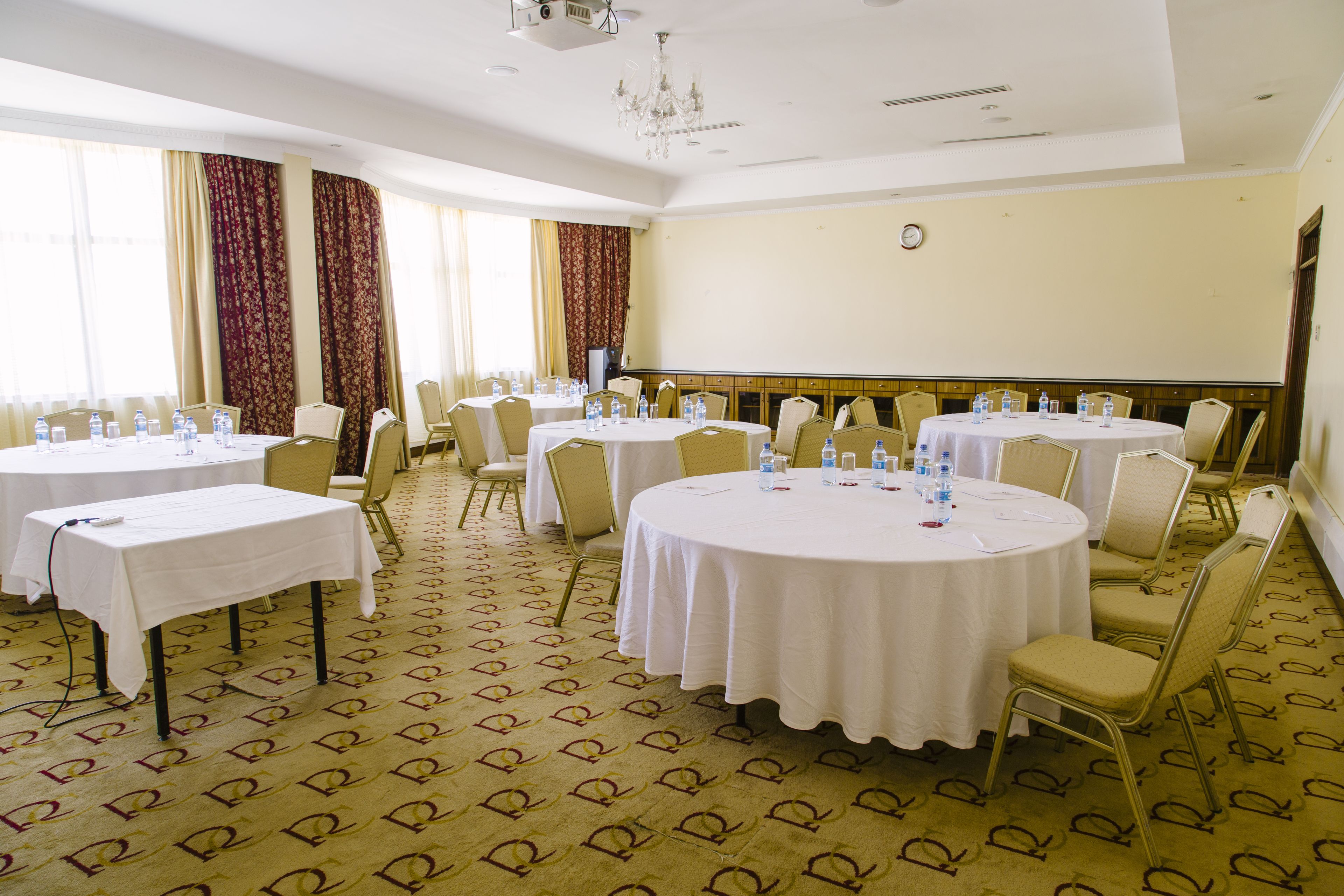 Une salle de conférence équipée de tables rondes, de chaises et de bouteilles d’eau.