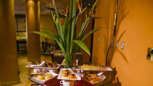 A buffet setup with various food items and a centerpiece of a tall plant. - Boma Inn Nairobi (Nairobi)