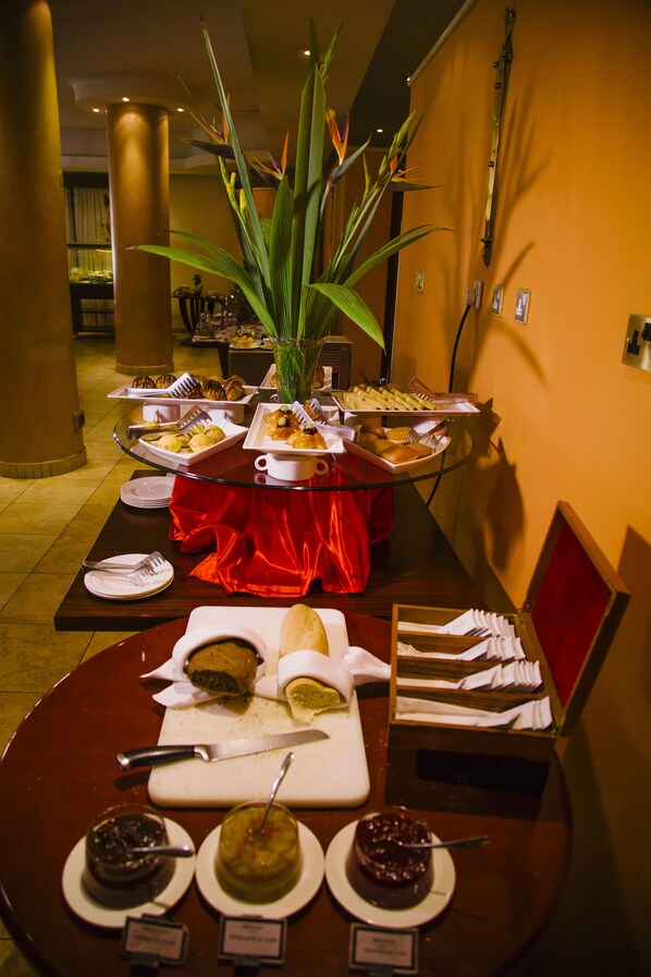 A buffet setup with various food items and a centerpiece of a tall plant. - Boma Inn Nairobi (Nairobi)