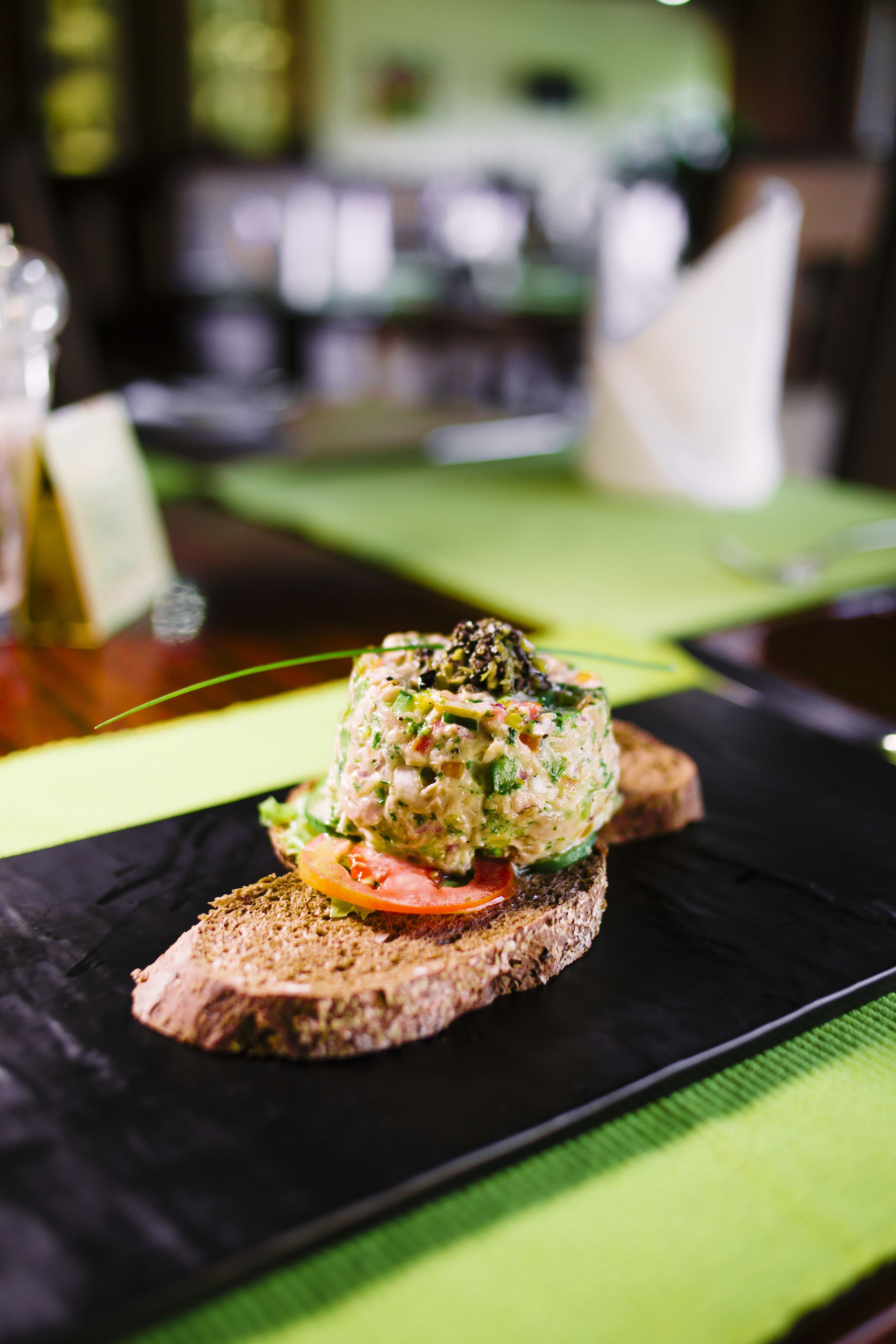Ein Teller mit einem schwarzen Untertasse, darauf eine Scheibe Brot mit grüner Beilage.