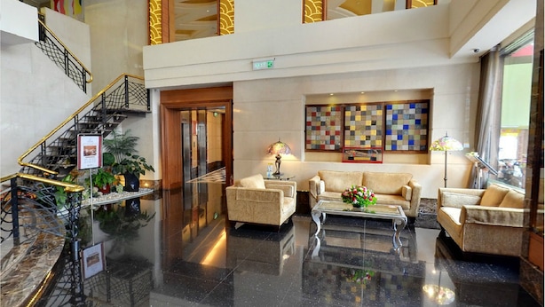 A spacious lobby with a marble floor, a staircase with golden railings, a sofa set, a coffee table, and a wall with a colorful quilt pattern. - Taipei International Hotel (Taipei)
