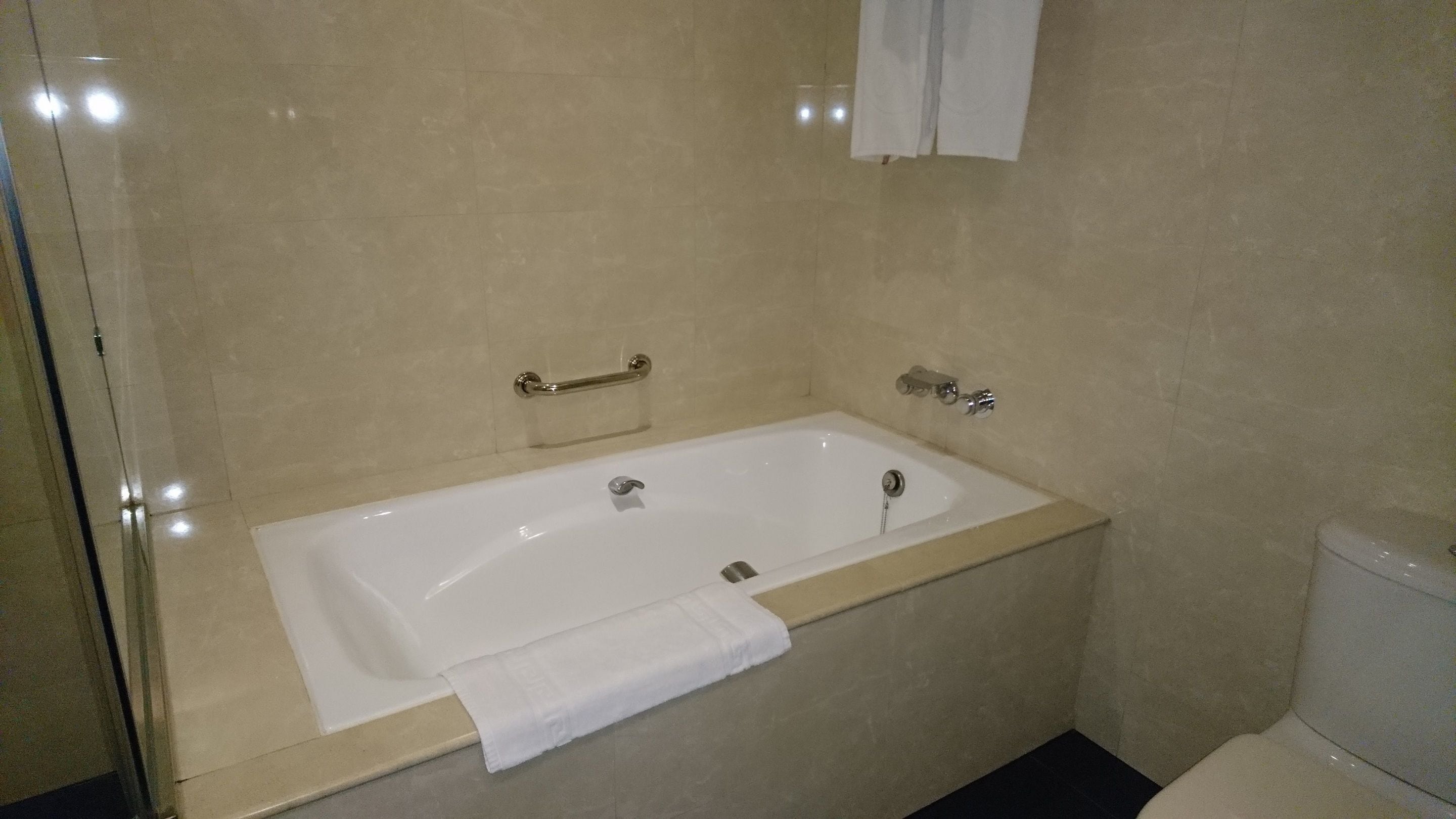 A bathroom with a white bathtub, a towel, and a toilet.