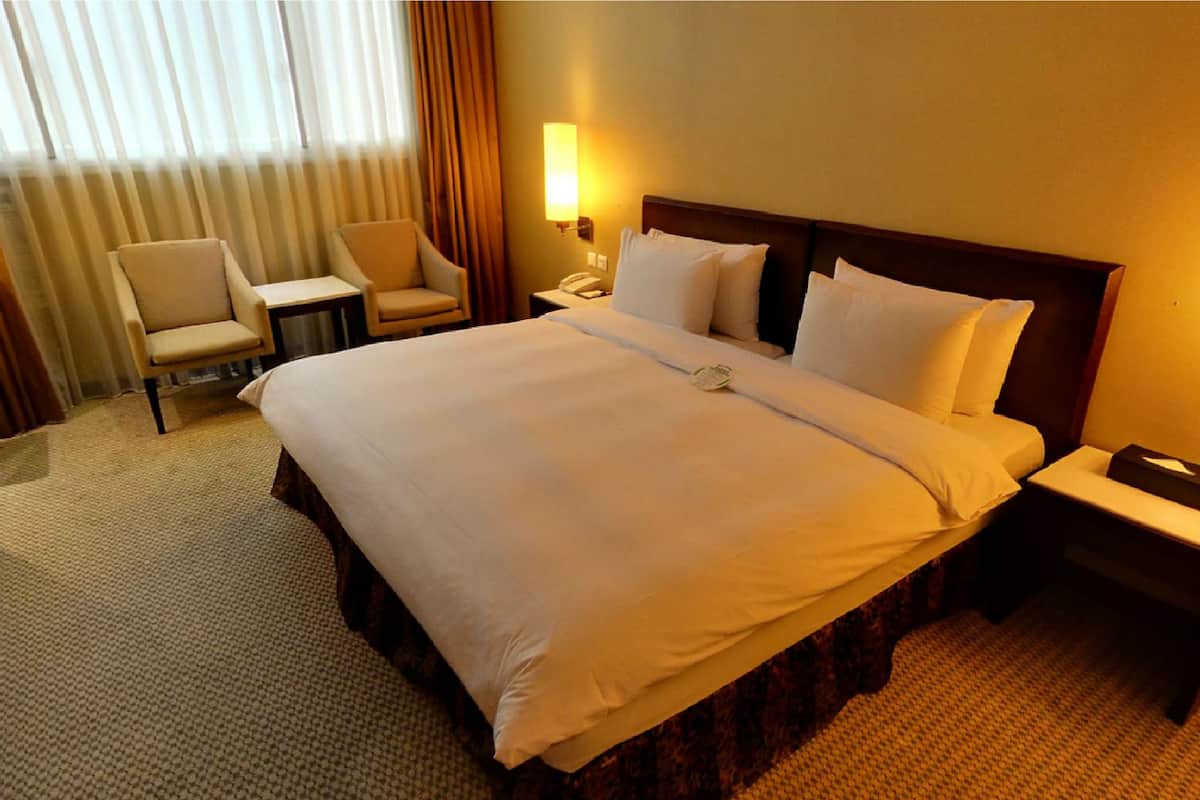 Une chambre d’hôtel avec un grand lit, deux tables de chevet, une chaise et un bureau.