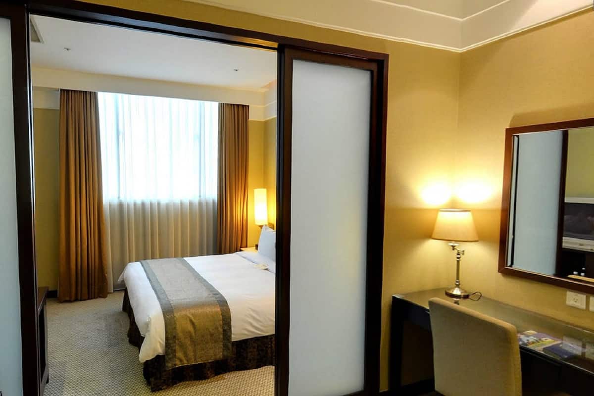 Une chambre d’hôtel avec un lit, un bureau doté d’une lampe et un miroir.