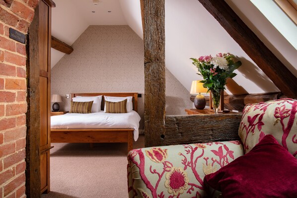 A bedroom with a wooden bed, a brick wall, and a sloped ceiling.