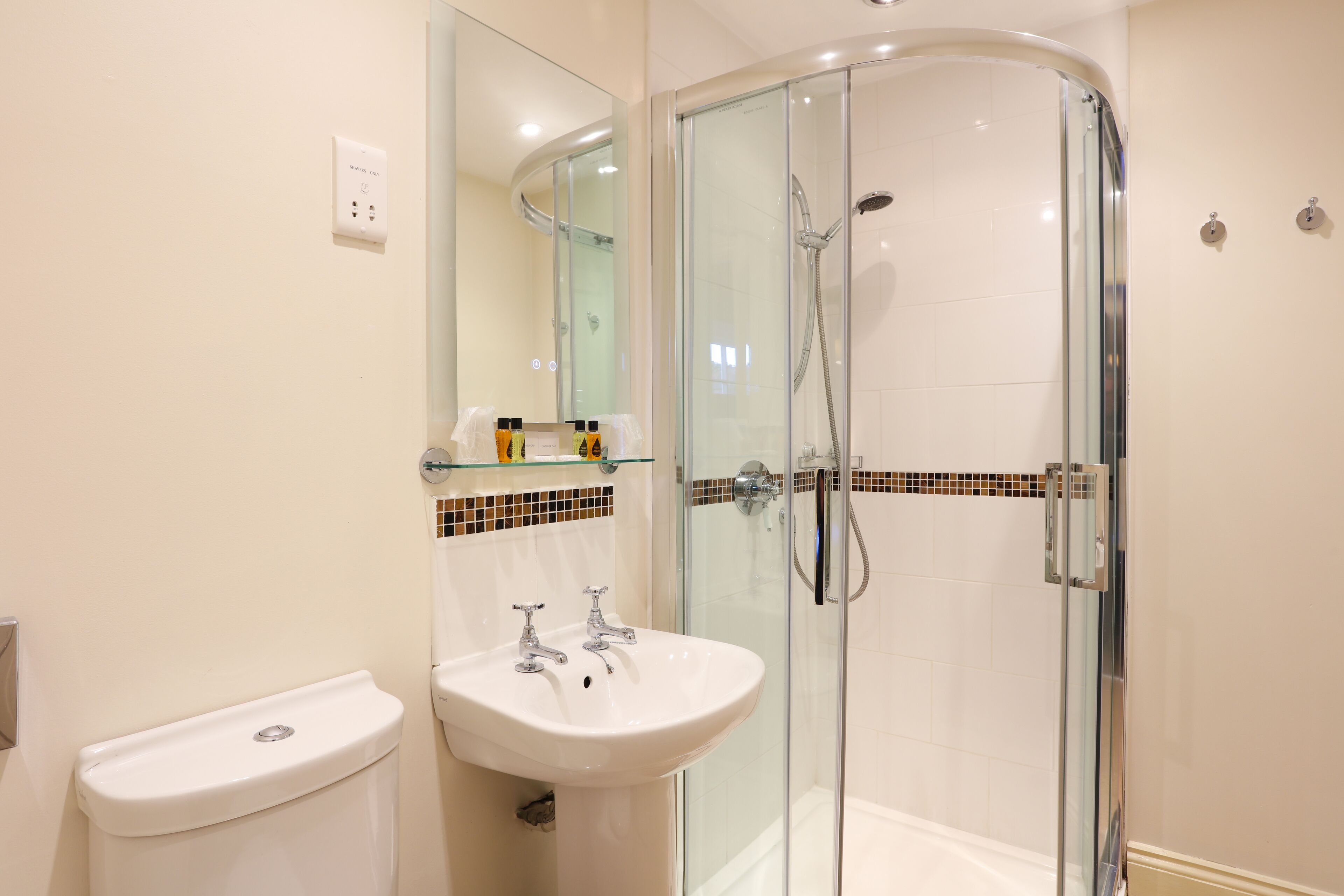 Un baño moderno con ducha de vidrio, un lavabo blanco y un inodoro.