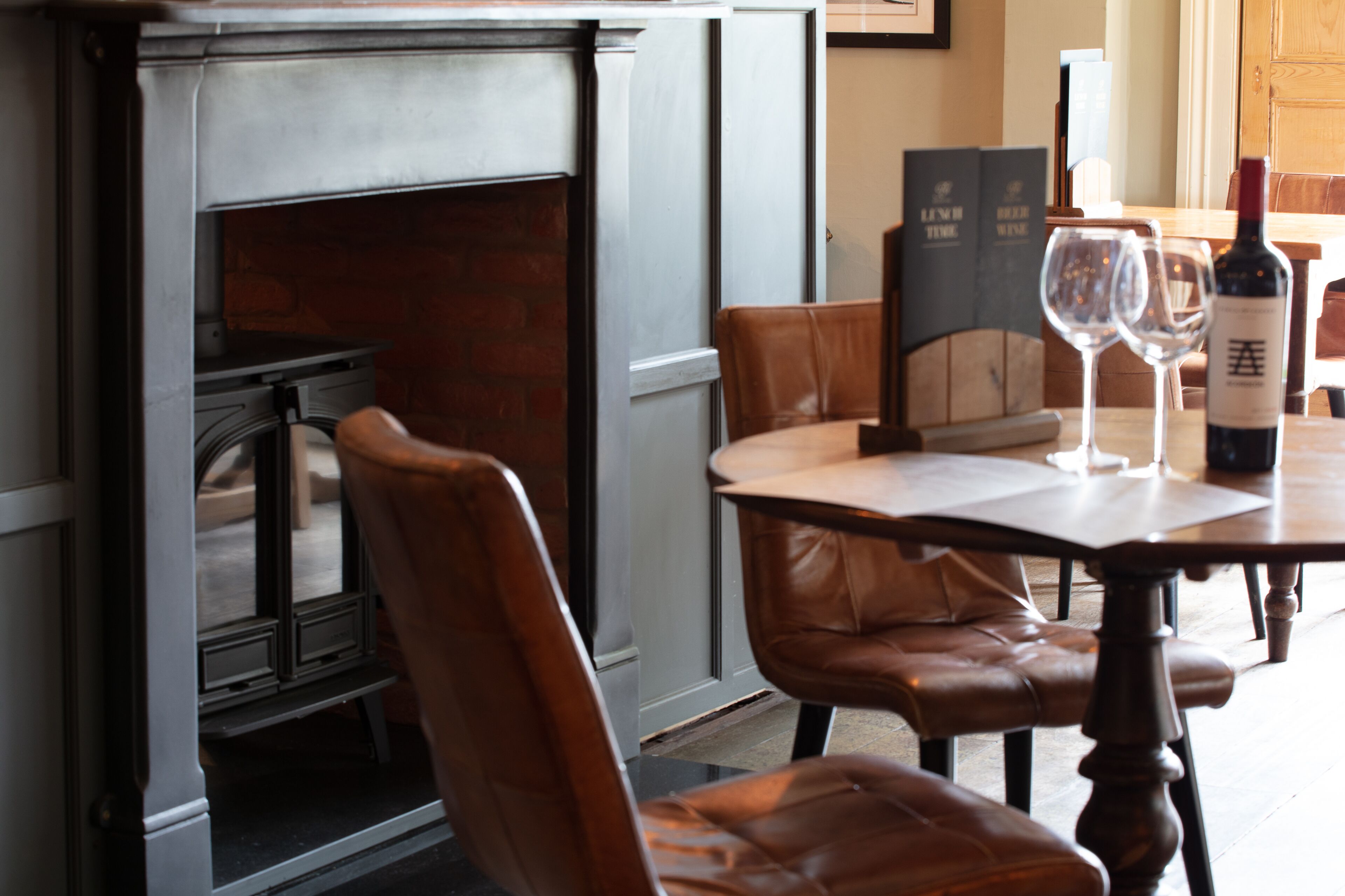A dining area with leather chairs, a table, and a fireplace.