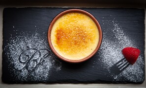 Postre en un bol sobre una tabla de pizarra con azúcar glas y una fresa.