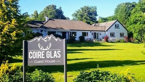 A guest house named COIRE GLAS with a well-maintained lawn and a traditional building.