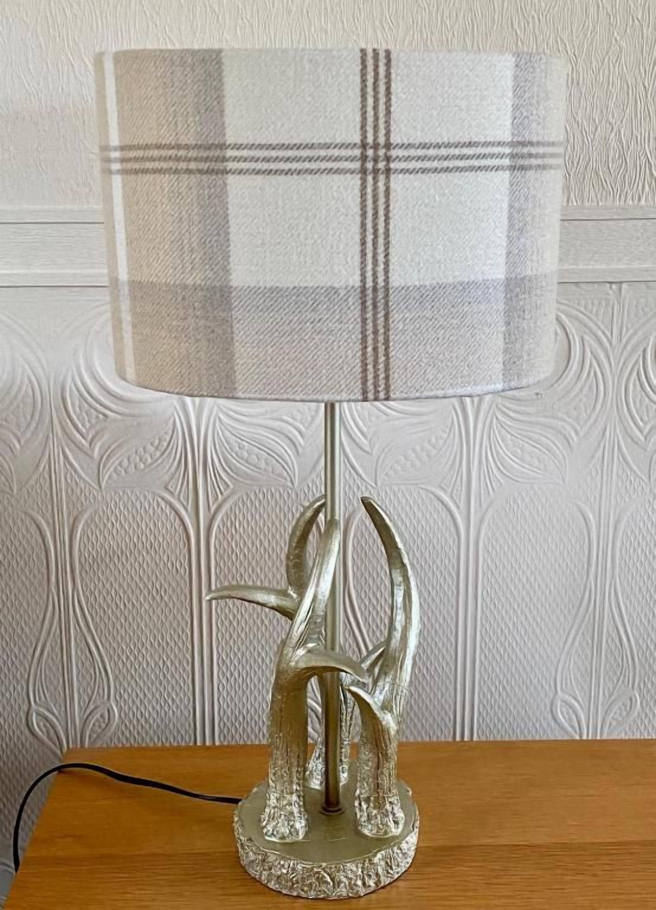 Una lámpara de mesa con pantalla estampada de cuadros y base metálica.