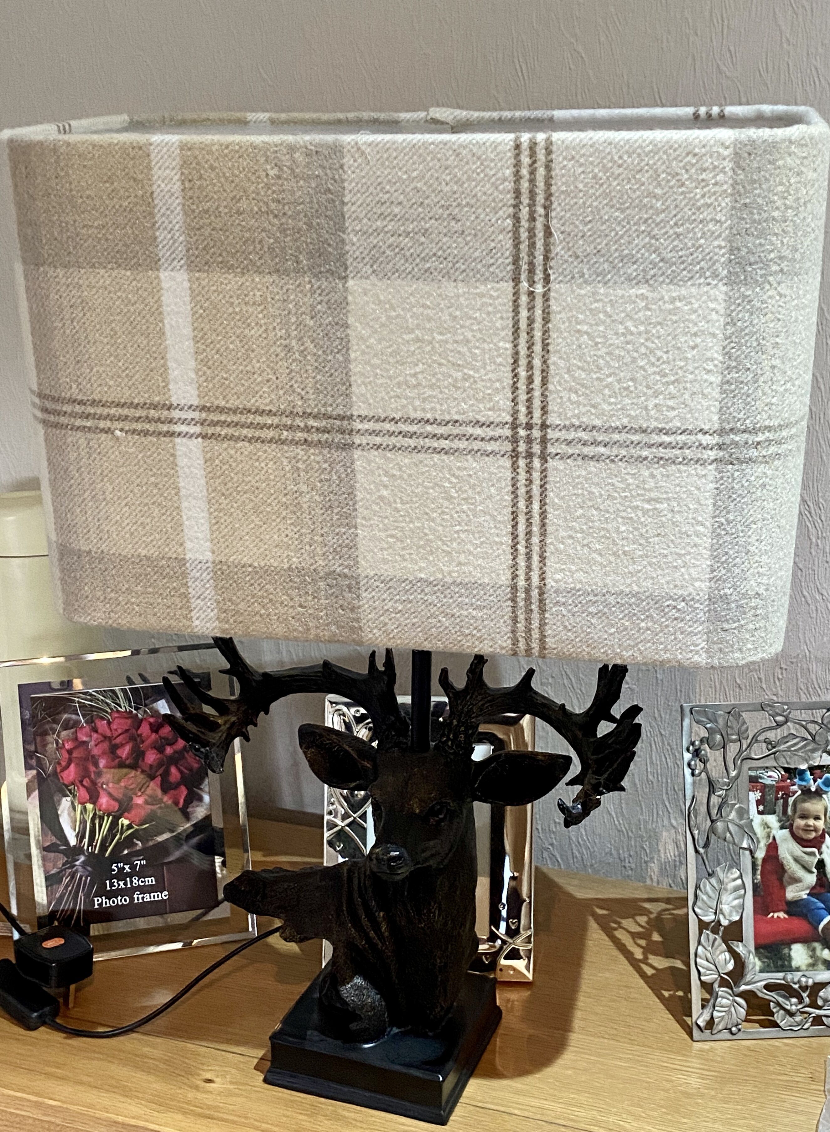 Una mesa con una escultura de cabeza de ciervo, un marco de fotos y un espejo.