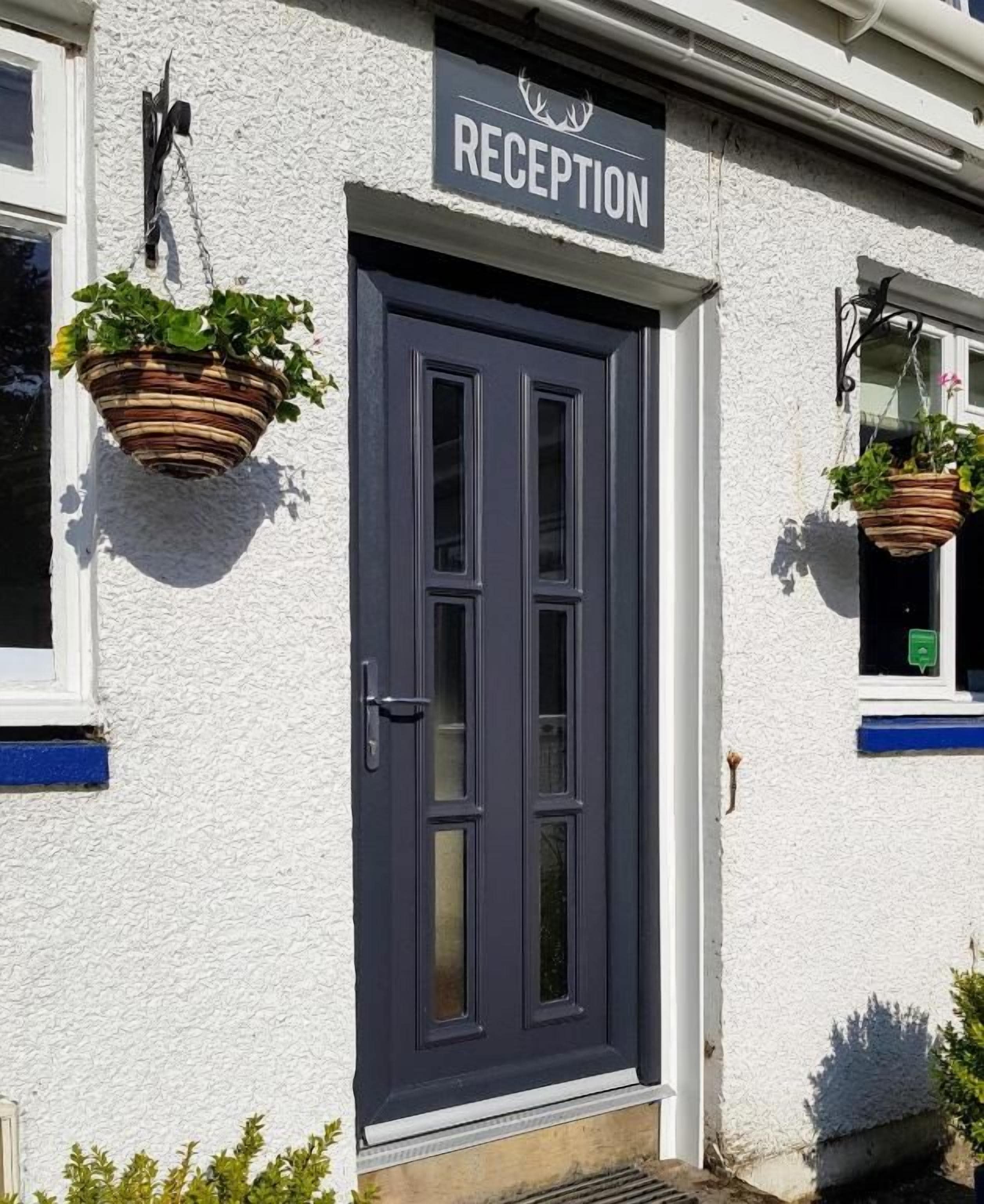 A reception door with a sign, a hanging plant, and a window with a hanging plant.