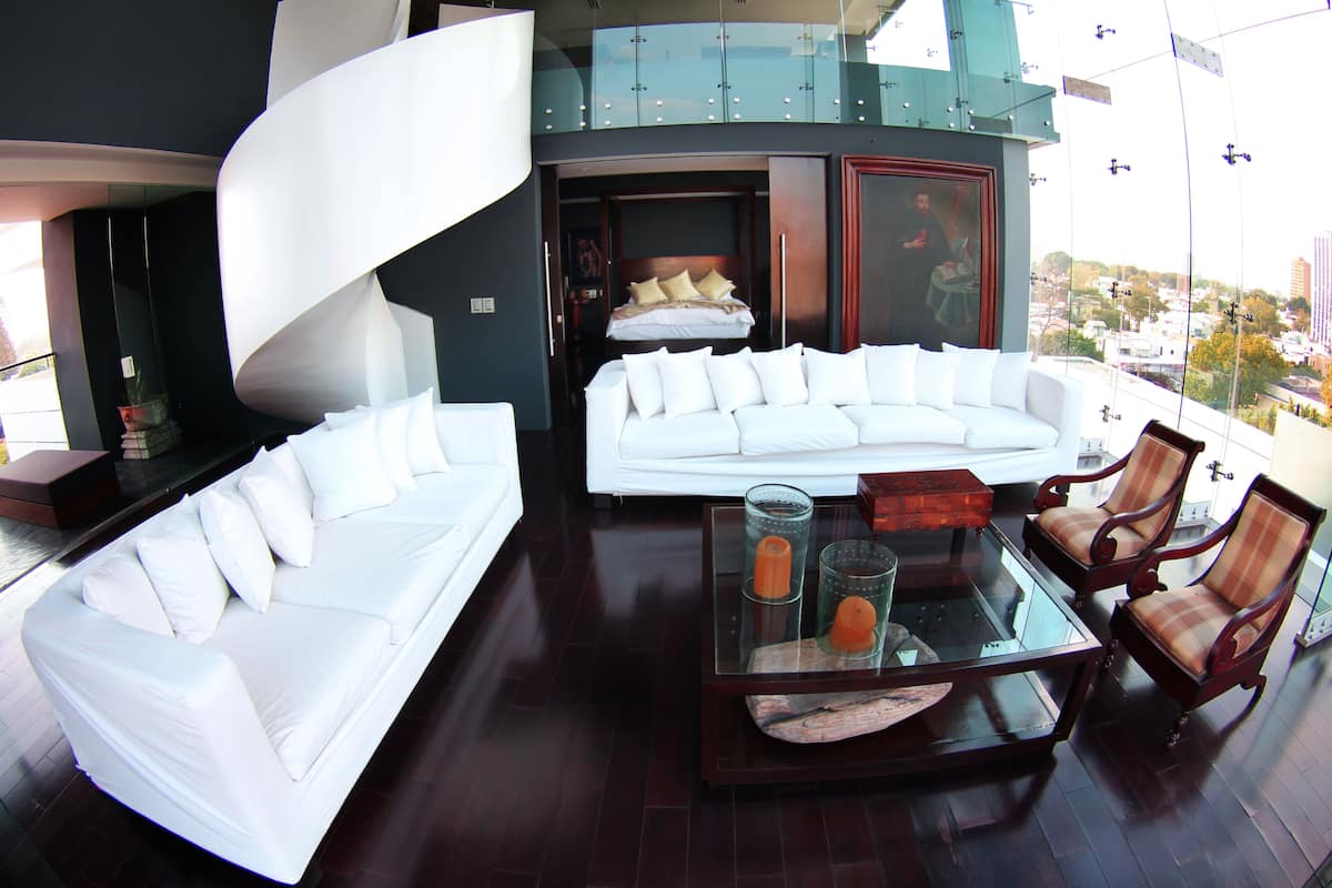 A modern living room with a white sofa, a glass coffee table, and a view of the city through large windows.