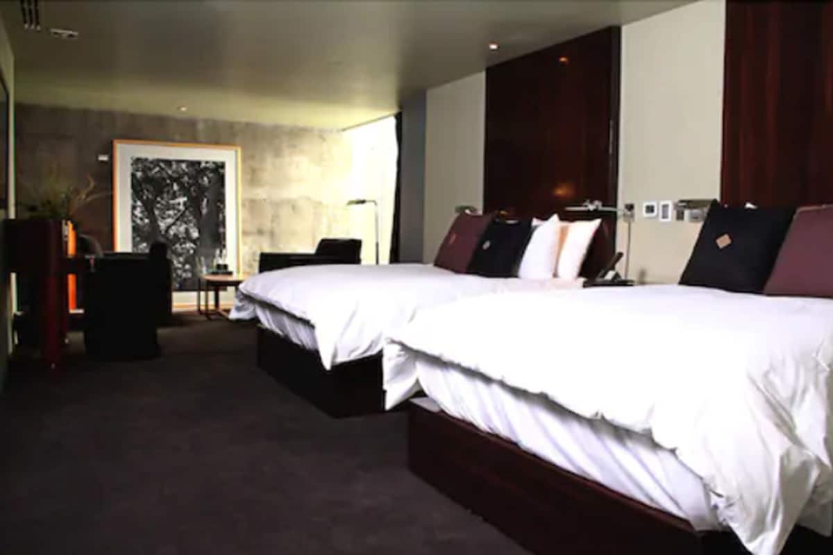 A modern hotel room with a large bed, a desk, and a chair.