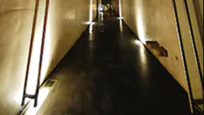 A narrow, dimly lit corridor with two parallel walls and a central walkway.