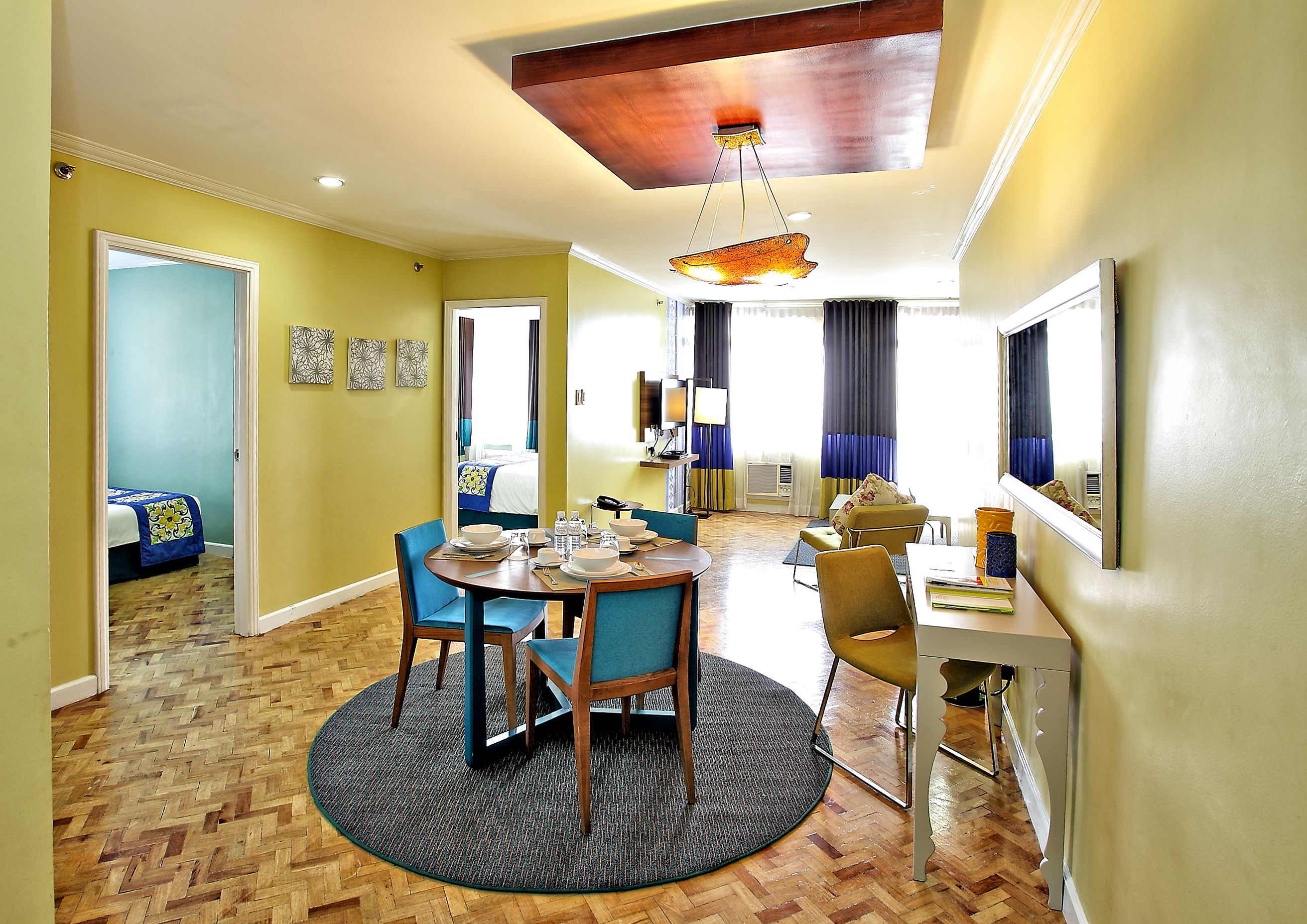 A hotel room with a dining area, a living area, and a bedroom.