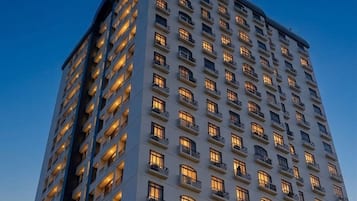 A high-rise hotel with multiple floors and balconies, under a night sky with a visible moon.