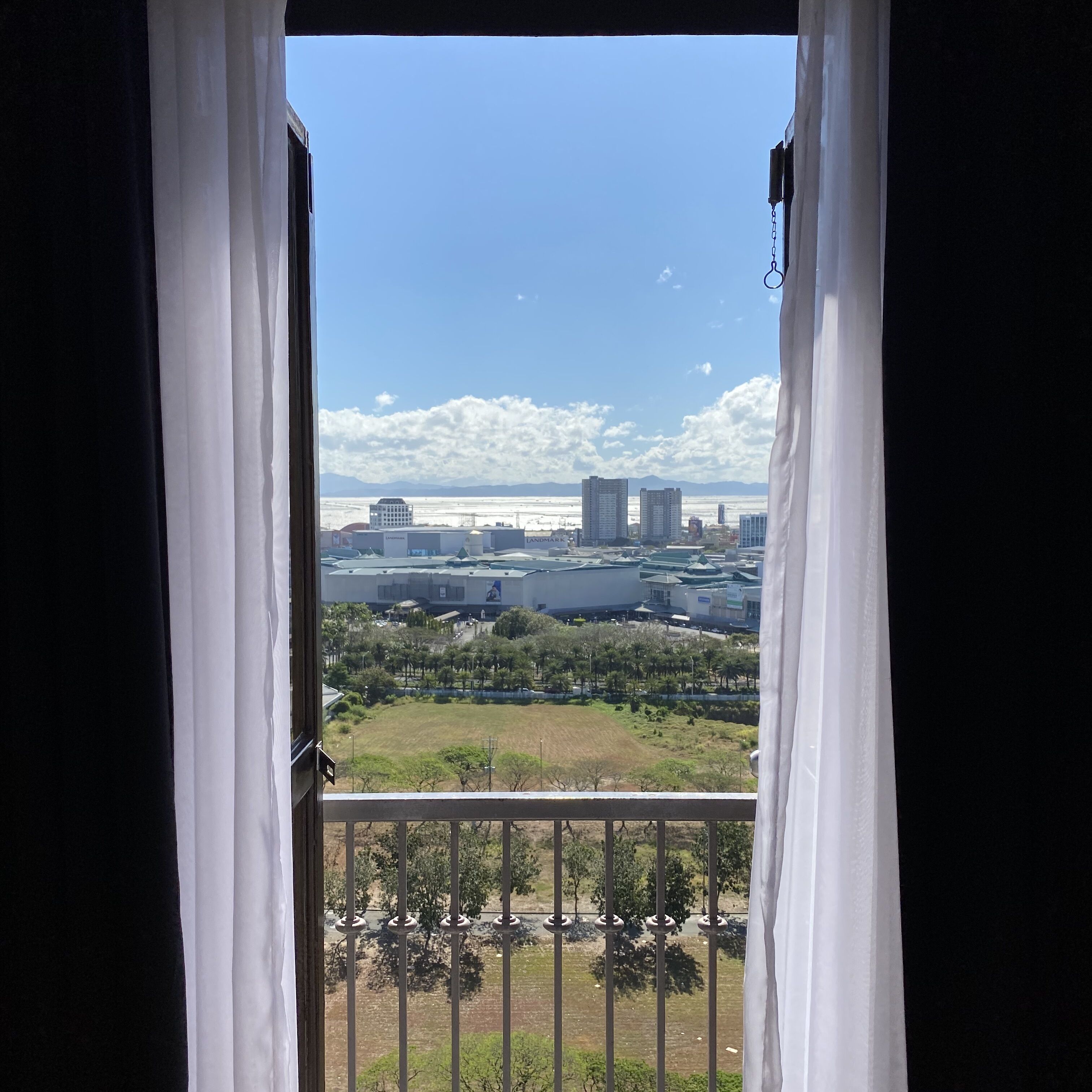 A balcony with a view of a cityscape, including buildings and a body of water.