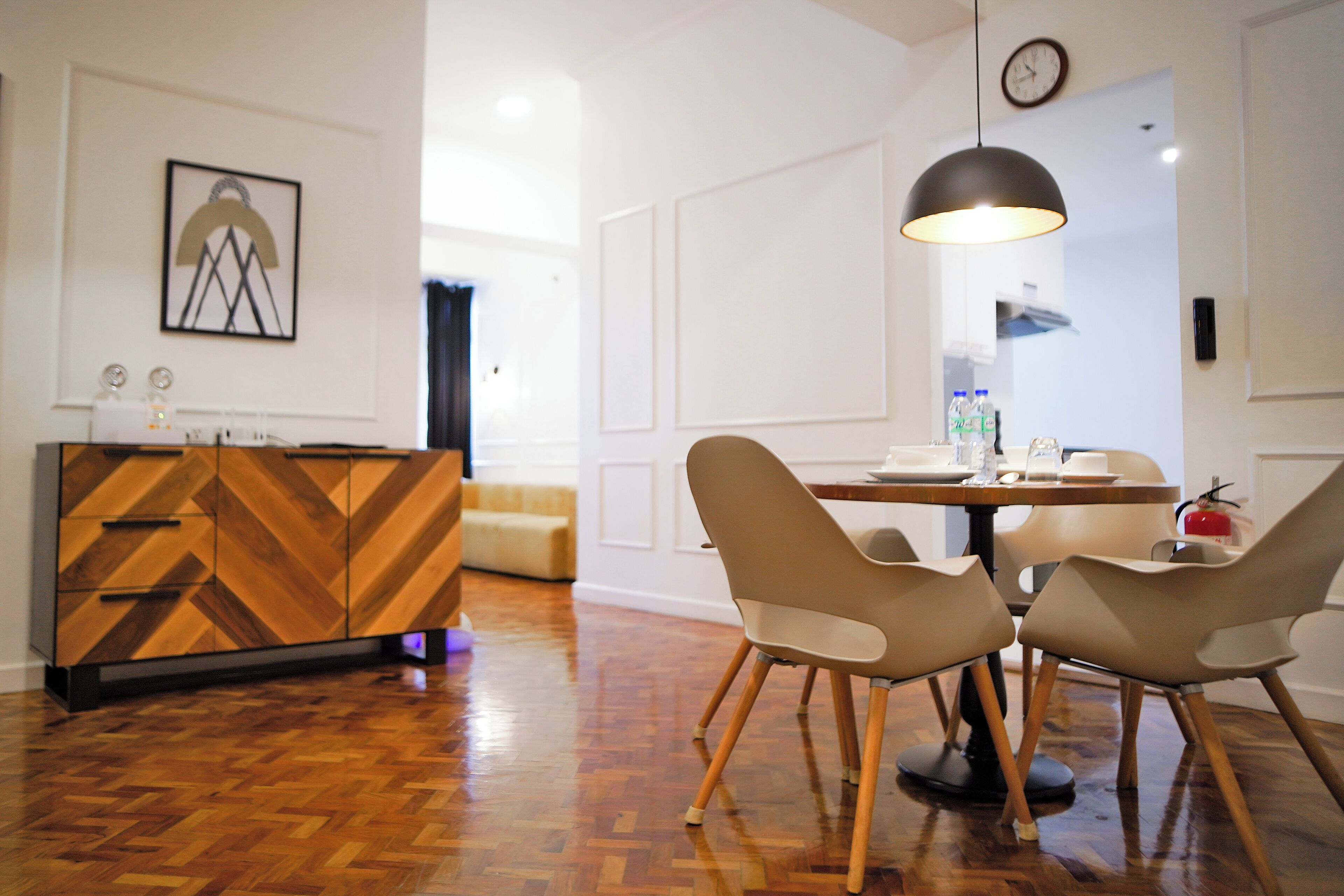 A modern dining area with a wooden herringbone floor, a round table, and two beige chairs.