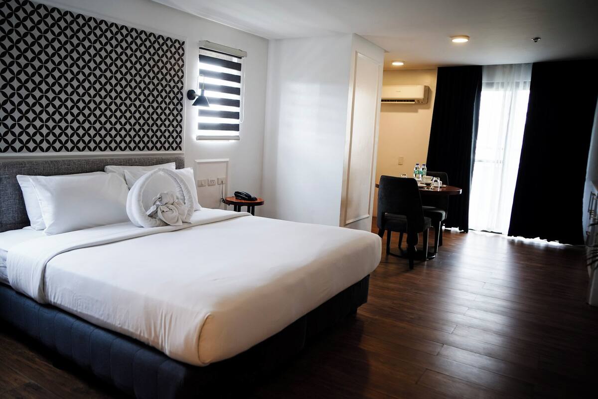 A hotel room with a large bed, a desk, and a chair.