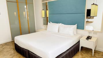 Ein Hotelzimmer mit einem großen Bett, einem Nachttisch, einem Telefon und einem Spiegel.