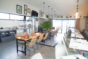 A modern dining area with a long table, chairs, and a bar area. - Parque Espana Residence Hotel (Muntinlupa)