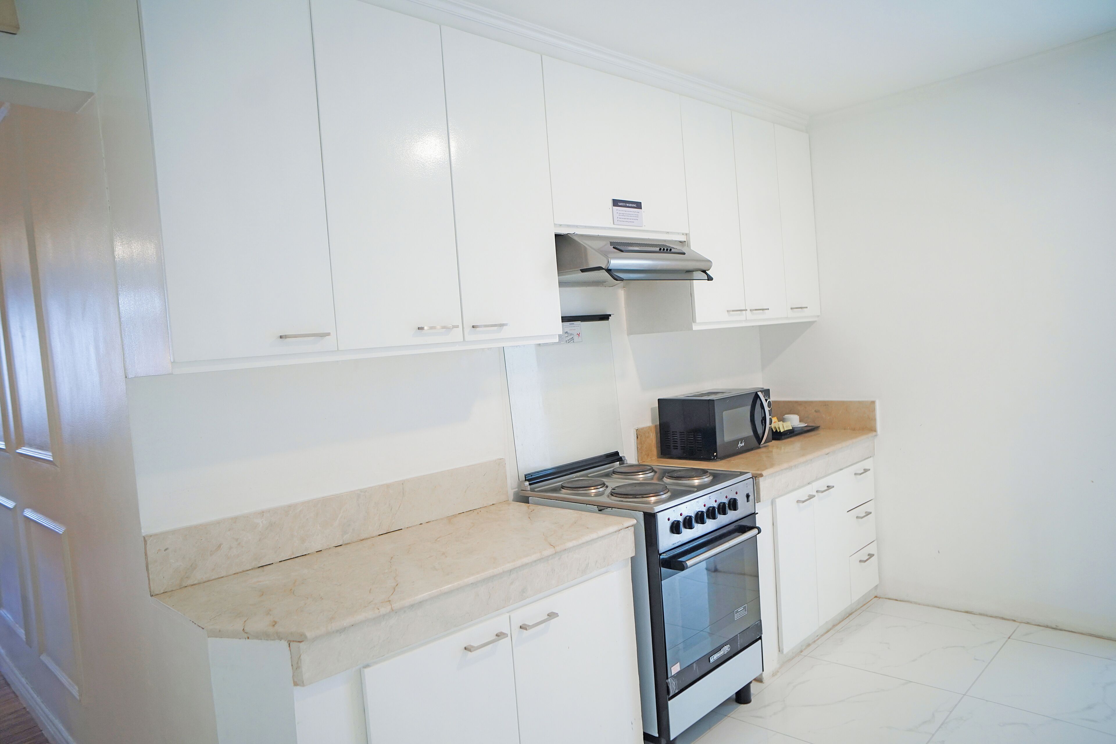 A kitchen with white cabinets, a stove, an oven, and a microwave.