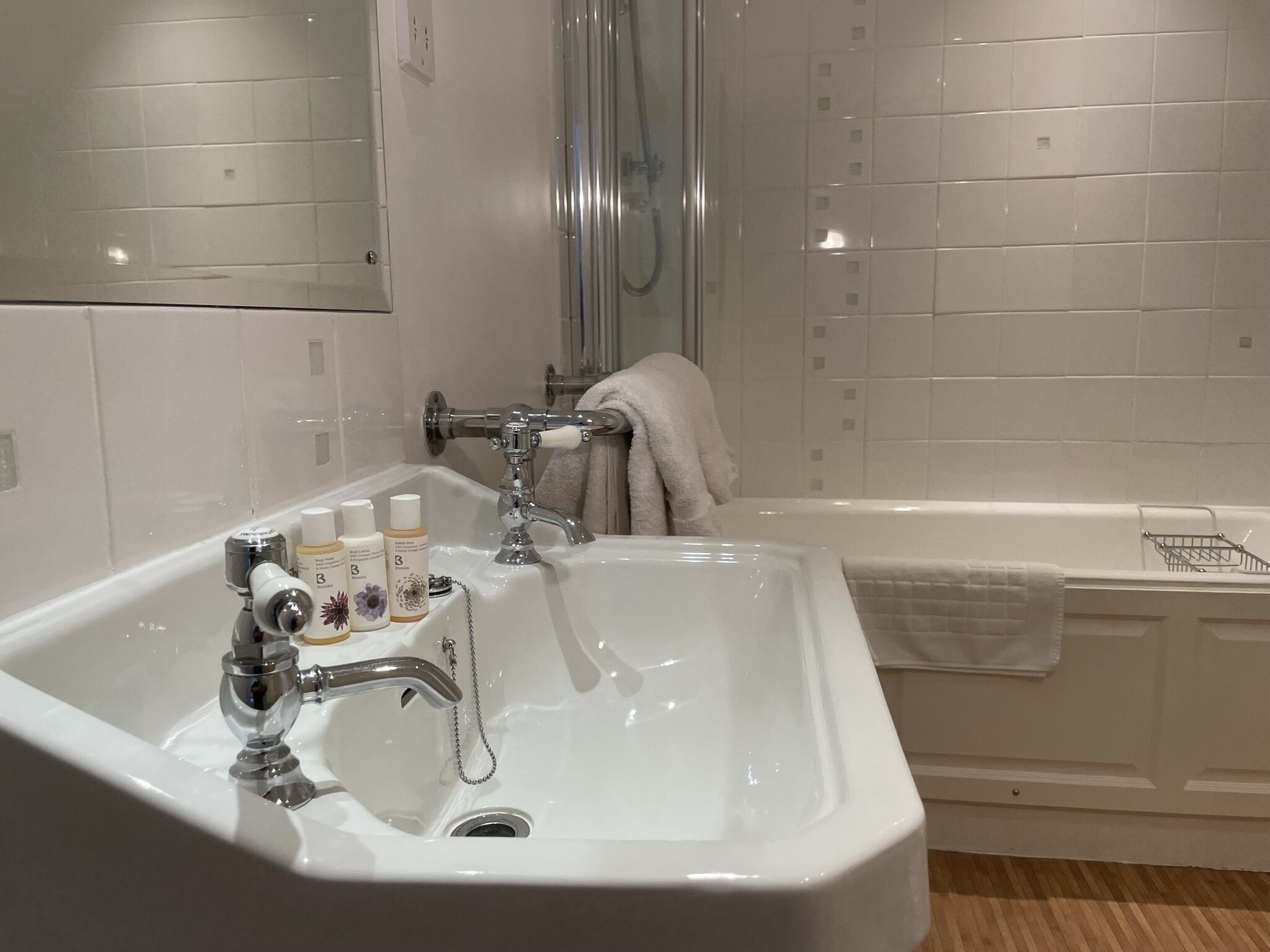 A bathroom with a white sink, a bathtub, and a shower. There are toiletries on the sink.