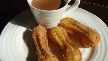 Lautasella on churroja ja kupissa kahvia.