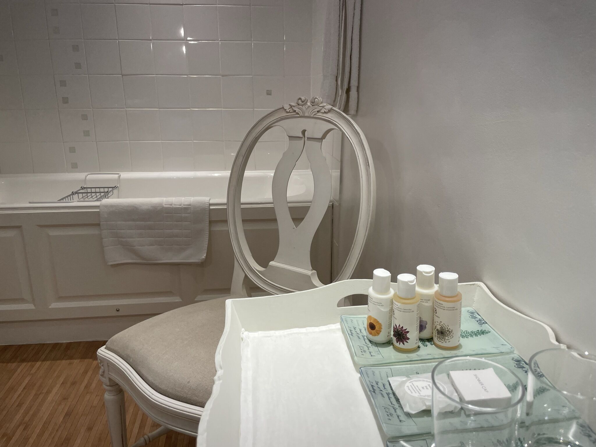 Un bagno con una vasca, una sedia bianca e un tavolo con articoli da toilette.
