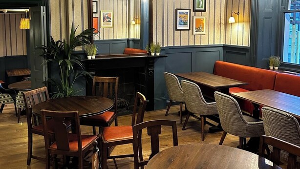 A dining area with striped wallpaper, a round wooden table, and a red bench.