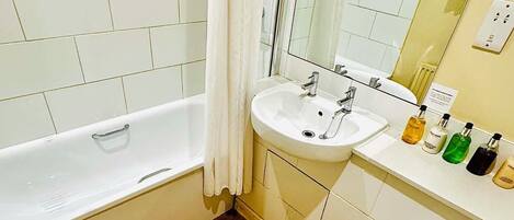 A bathroom with a bathtub, a sink, a toilet, and a mirror.