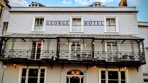 A building with 'GEORGE HOTEL' signage, a balcony with railings, and a small awning.