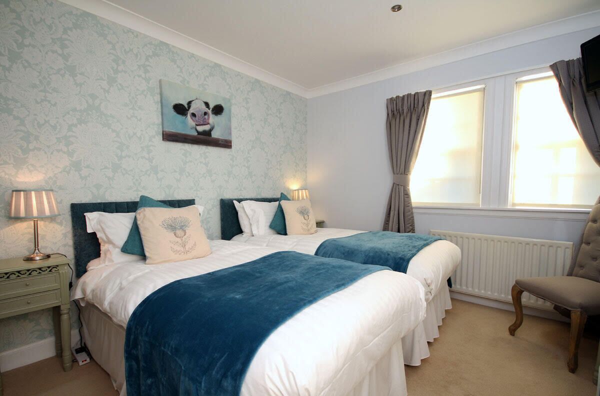 A hotel room with two beds, a nightstand, a chair, a window with curtains, and a wall with a panda painting.