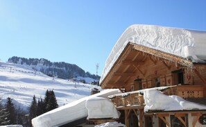 Cozy chalet surrounded by a snowy ski slope, offering breathtaking views and a warm porch.