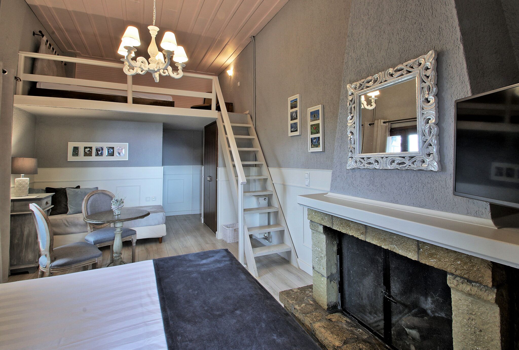 Un dormitorio con una cama litera, chimenea, televisor y candelabro.