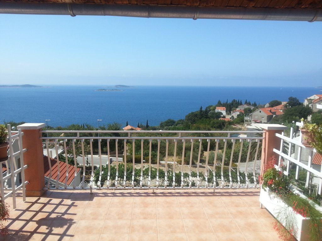 A balcony with a view of the sea and a coastal town.