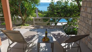 Un patio con dos sillas y una mesa, una botella de vino y un frutero.