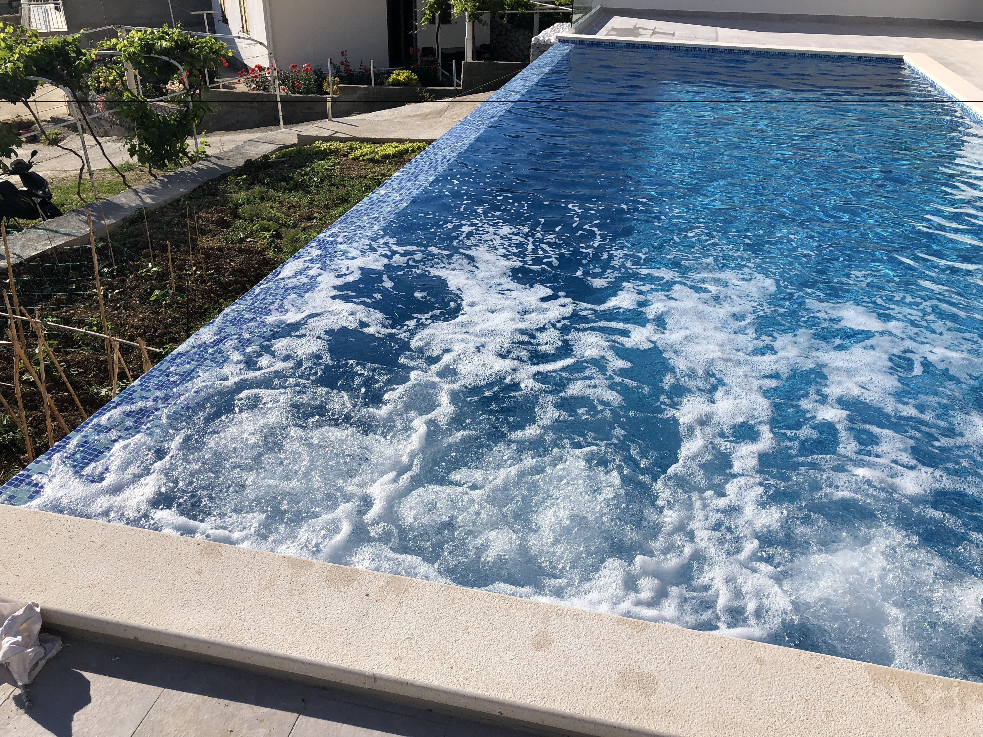 Ein rechteckiger Swimmingpool mit Fliesenrand und Betonumrandung.