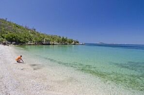 A clear beach with a person in an orange shirt. - Apartmani Ana (Zupa dubrovacka)