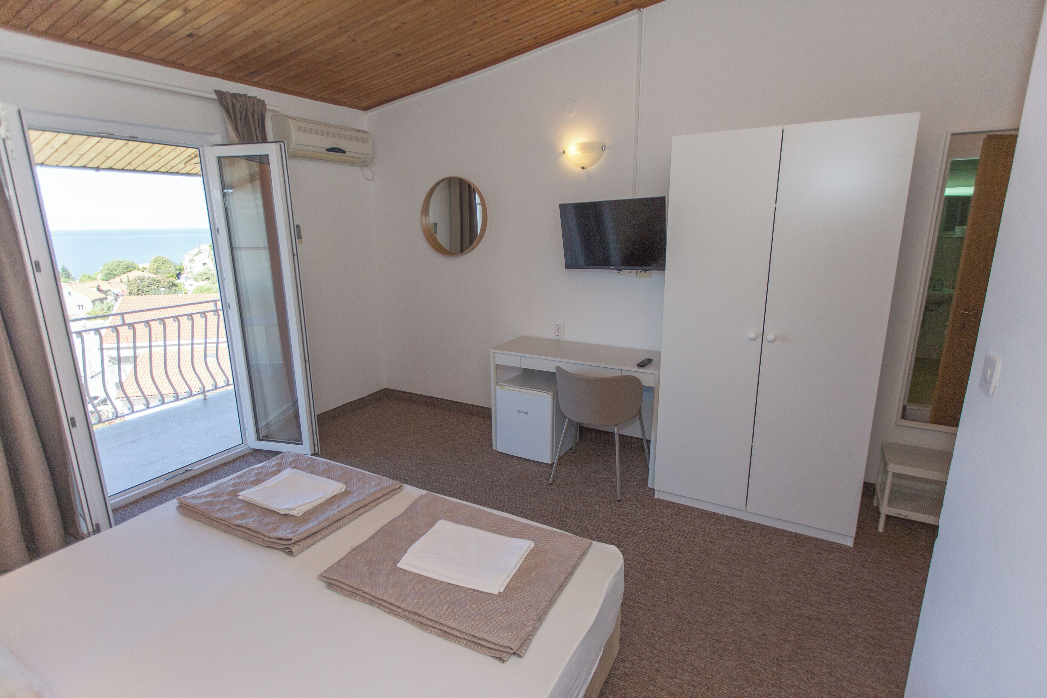 A bedroom with a bed, a desk, a TV, and a wardrobe.