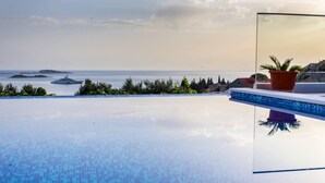 Una vista despejada de una piscina infinita con vistas al mar y a islas distantes.