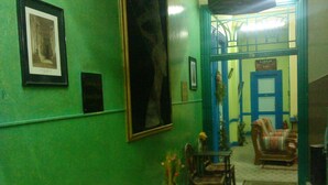 A room with green walls, a framed picture, a wooden table with chairs, a sofa, and a door labeled "KARNAK". - Richmond Hotel (Cairo)