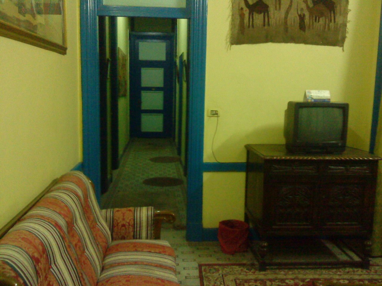 A narrow hallway with a sofa and a wooden cabinet with a television on top.