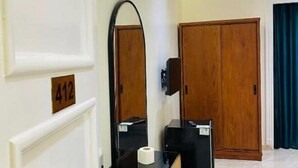 A hotel room with a wooden door, a mirror, a black desk with a telephone, and a number sign '412' on the wall. - Richmond Hotel (Cairo)