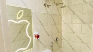 A bathroom with marble tiles, a toilet, a shower, and a mirror with an apple design. - Richmond Hotel (Cairo)