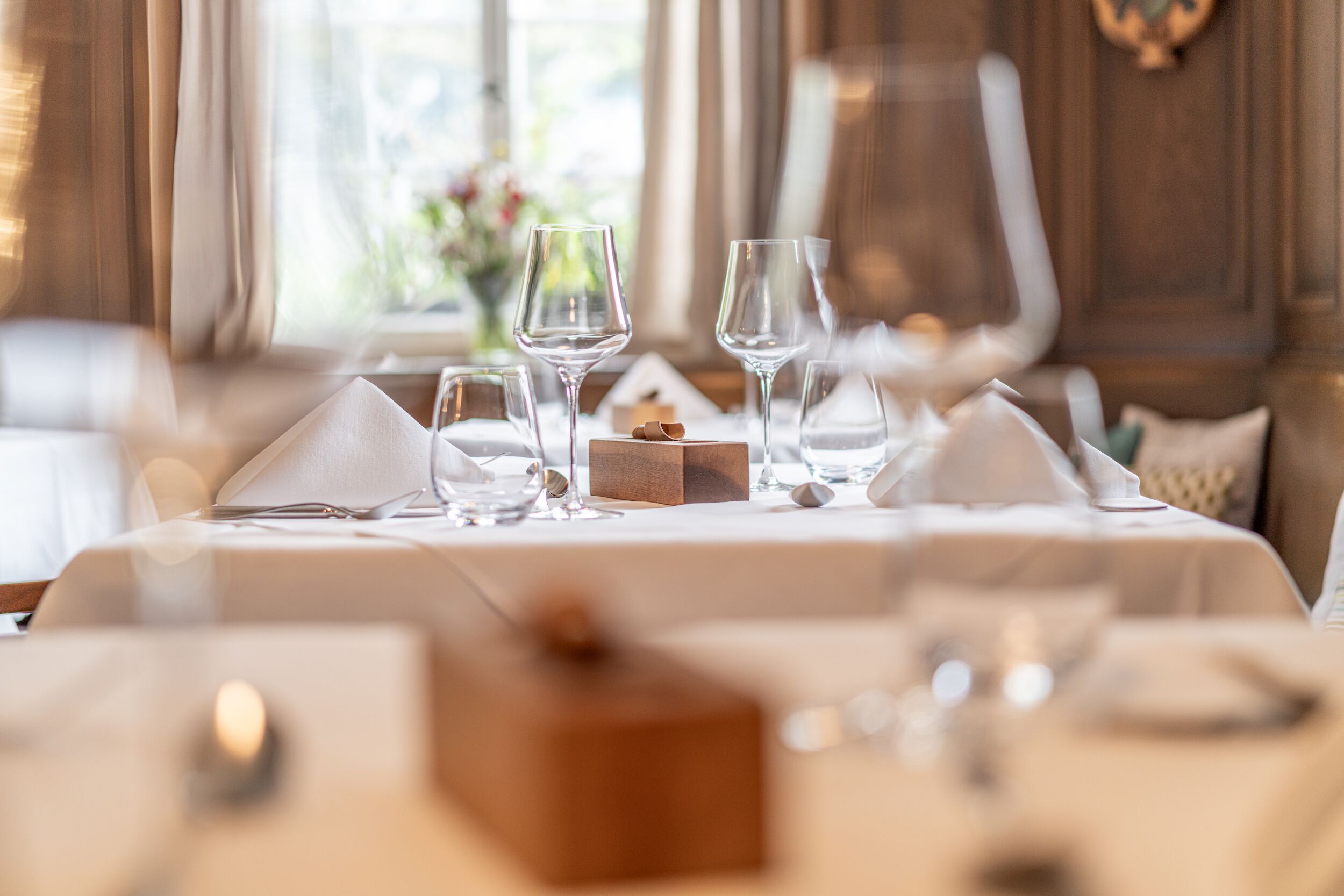 A dining table set with wine glasses, a small wooden box, and a candle.